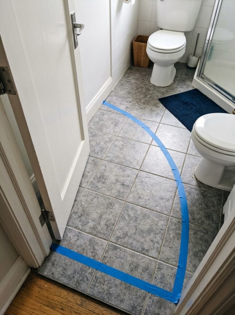 Bathroom door arc marked in tape on the floor, showing how much space the swing takes